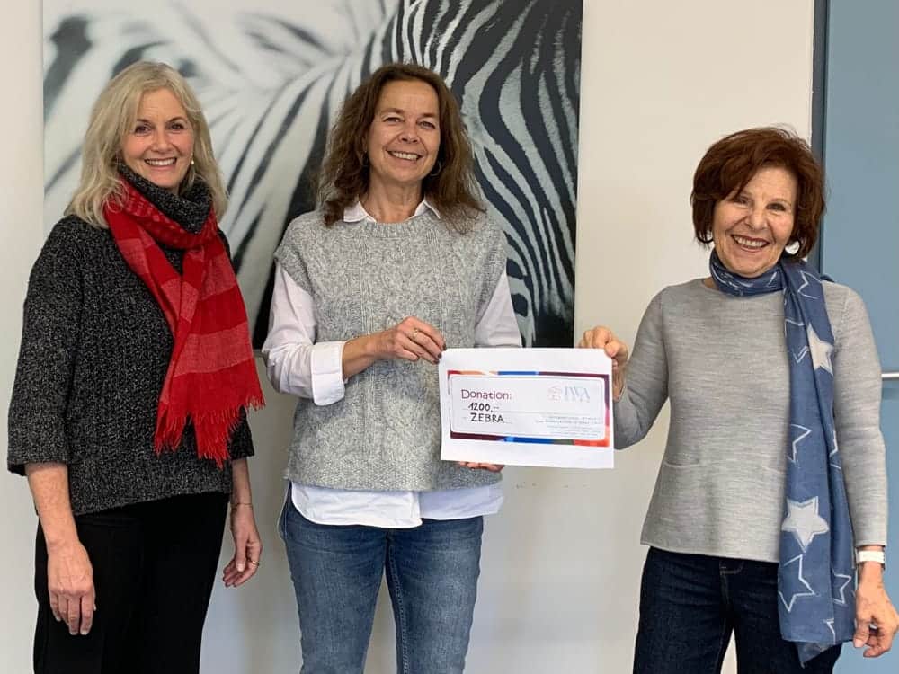 Three women hold a donation voucher